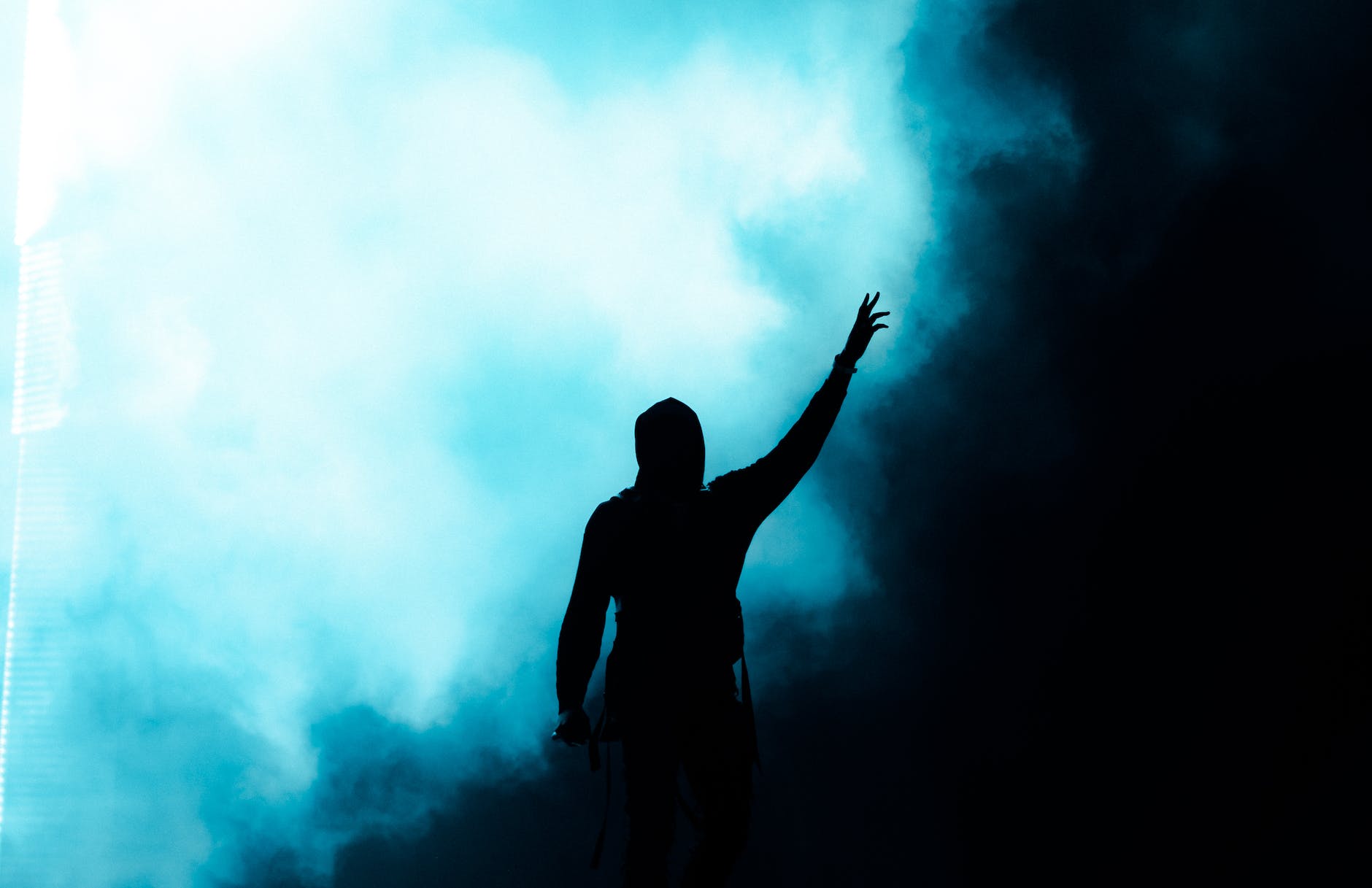 dark silhouette with hand reaching up for light in smoke
