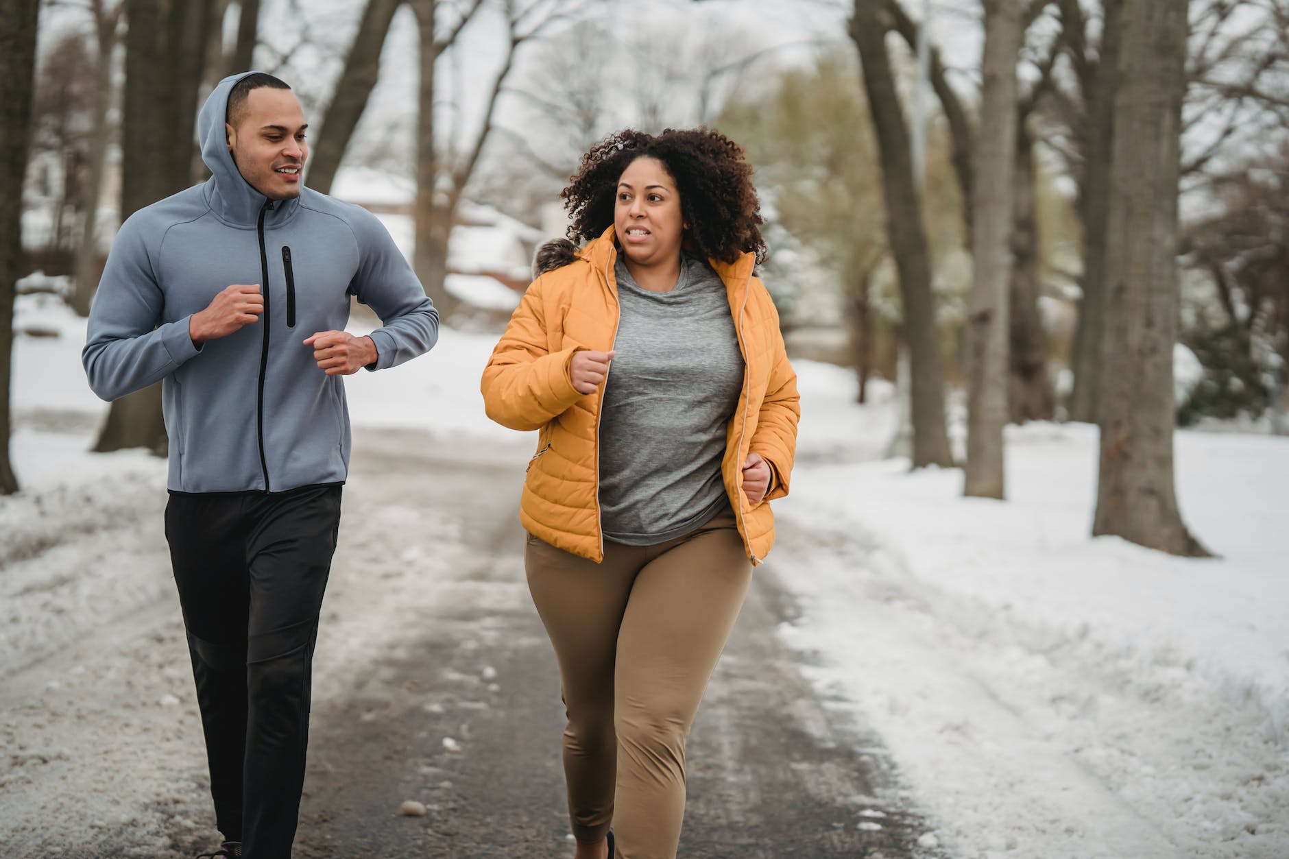 determined plump black woman jogging with trainer on pathway